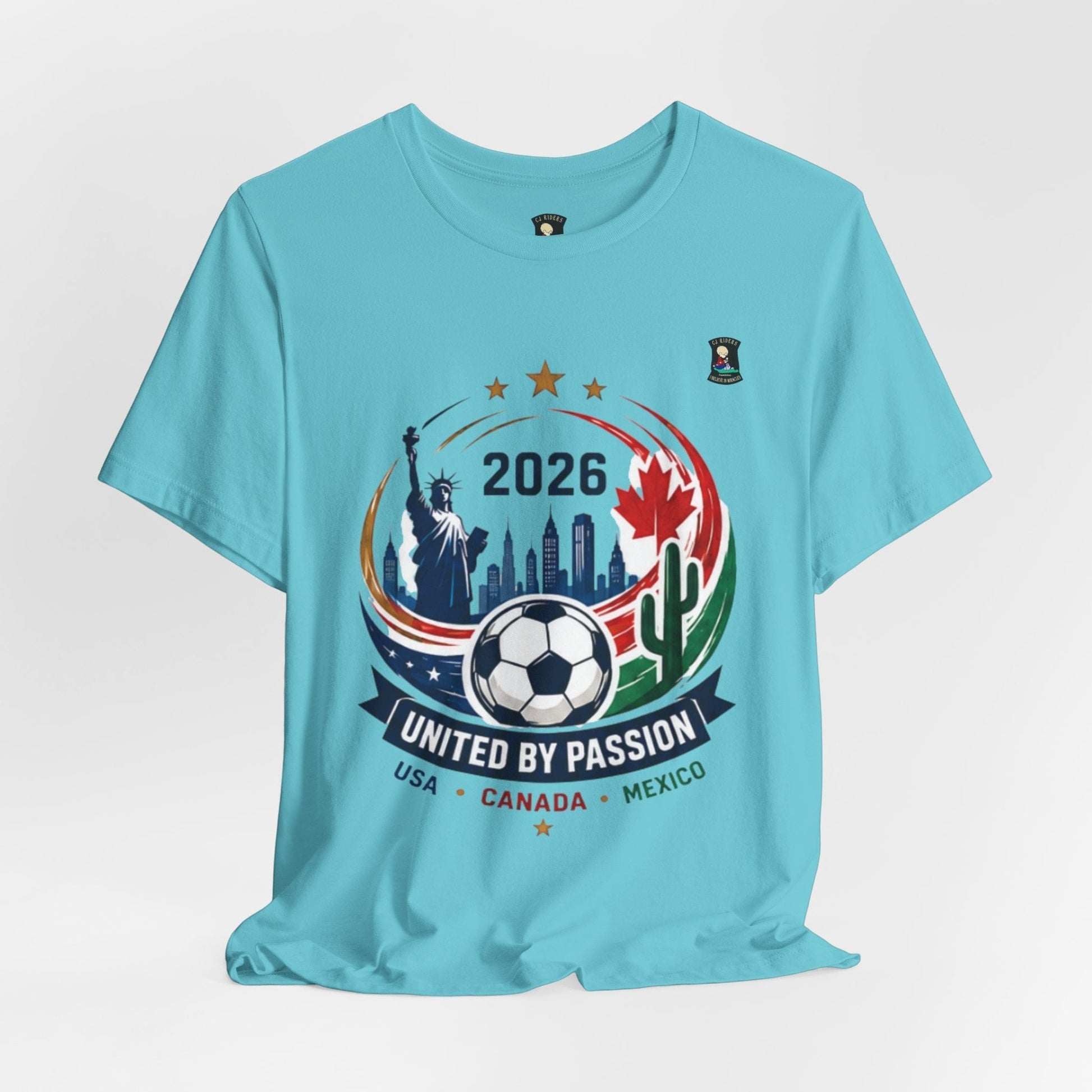 CJ Riders Foundation Store light blue 100% cotton t-shirt with 2026 soccer graphic featuring Statue of Liberty, Canadian maple leaf, Mexican flag, and soccer ball.