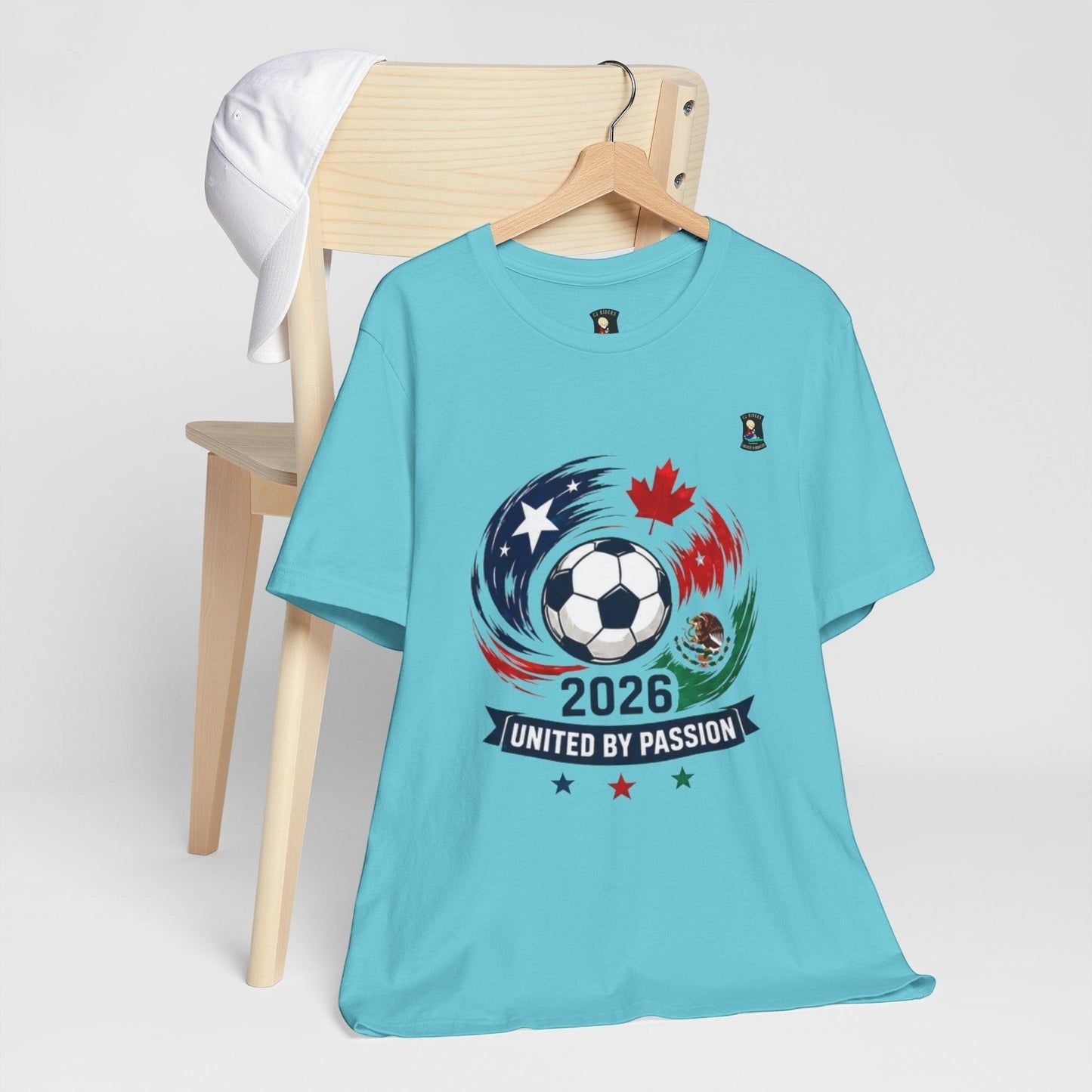 CJ Riders Foundation Store light blue 100% cotton t-shirt with 2026 United by Passion soccer graphic featuring USA, Canada, Mexico.