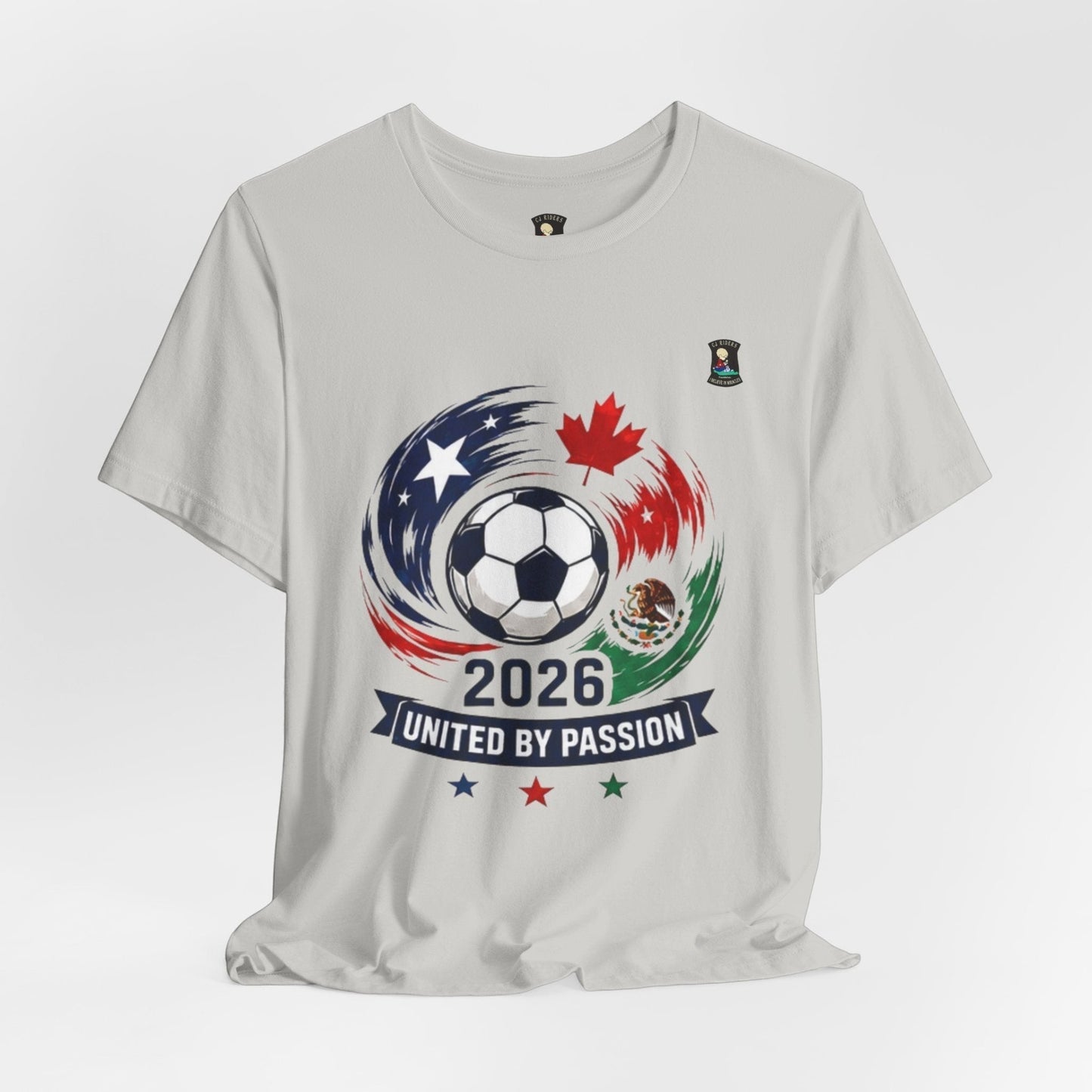 CJ Riders Foundation Store light grey 100% cotton t-shirt with 2026 soccer graphic featuring a ball, USA, Canada, Mexico flags and "United by Passion" text.