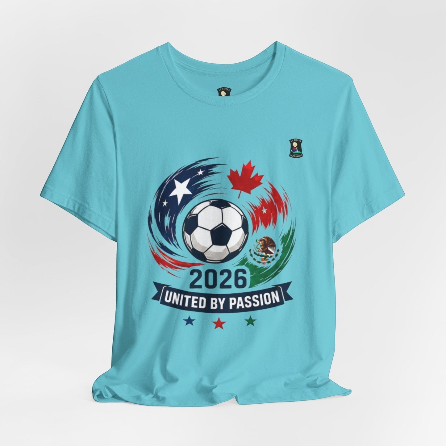 CJ Riders Foundation Store light blue 100% cotton t-shirt with 2026 soccer graphic featuring a ball, USA, Canada, Mexico flags, and "United by Passion" text.