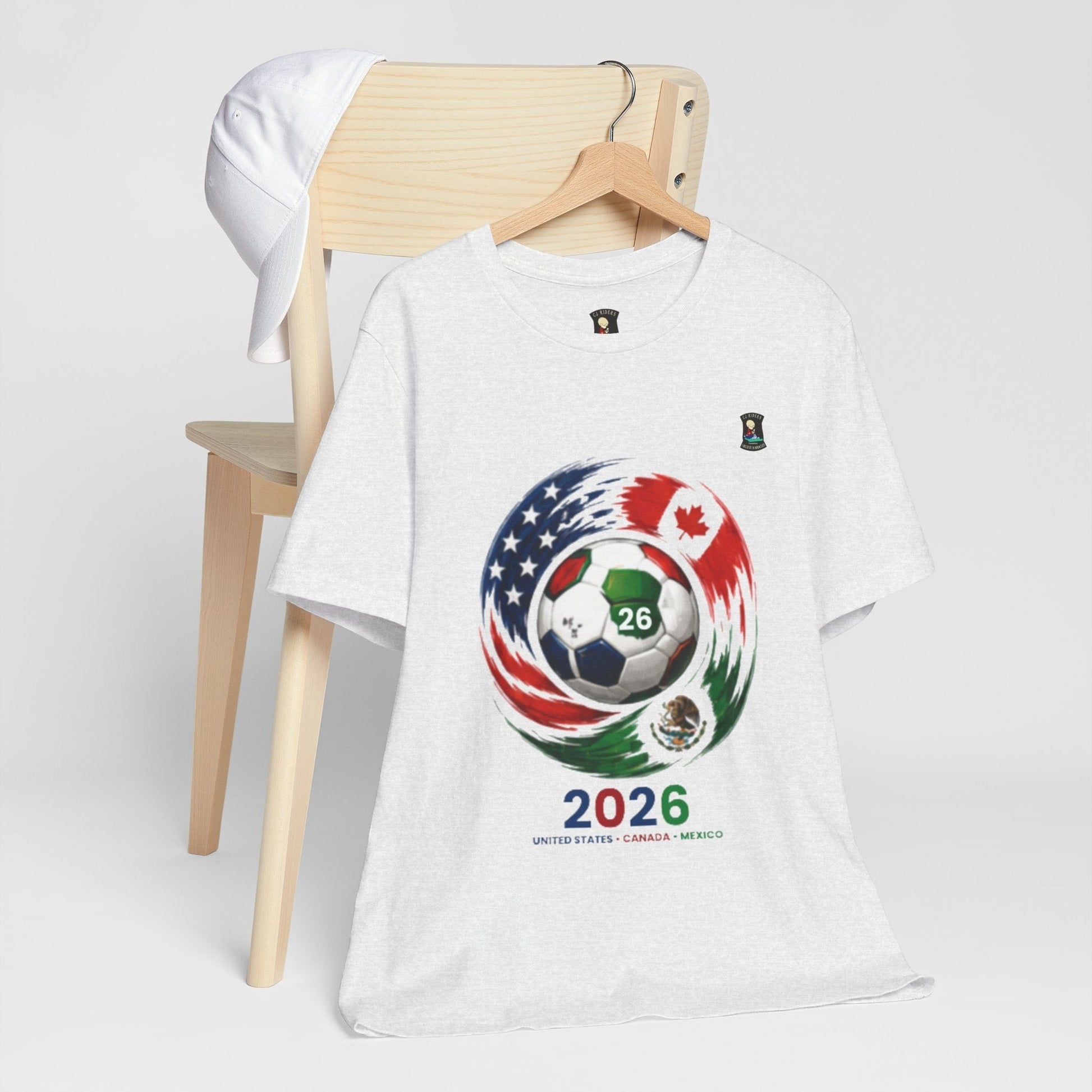 CJ Riders Foundation Store white 100% cotton t-shirt with 2026 soccer graphic featuring USA, Canada, Mexico flags and soccer ball.