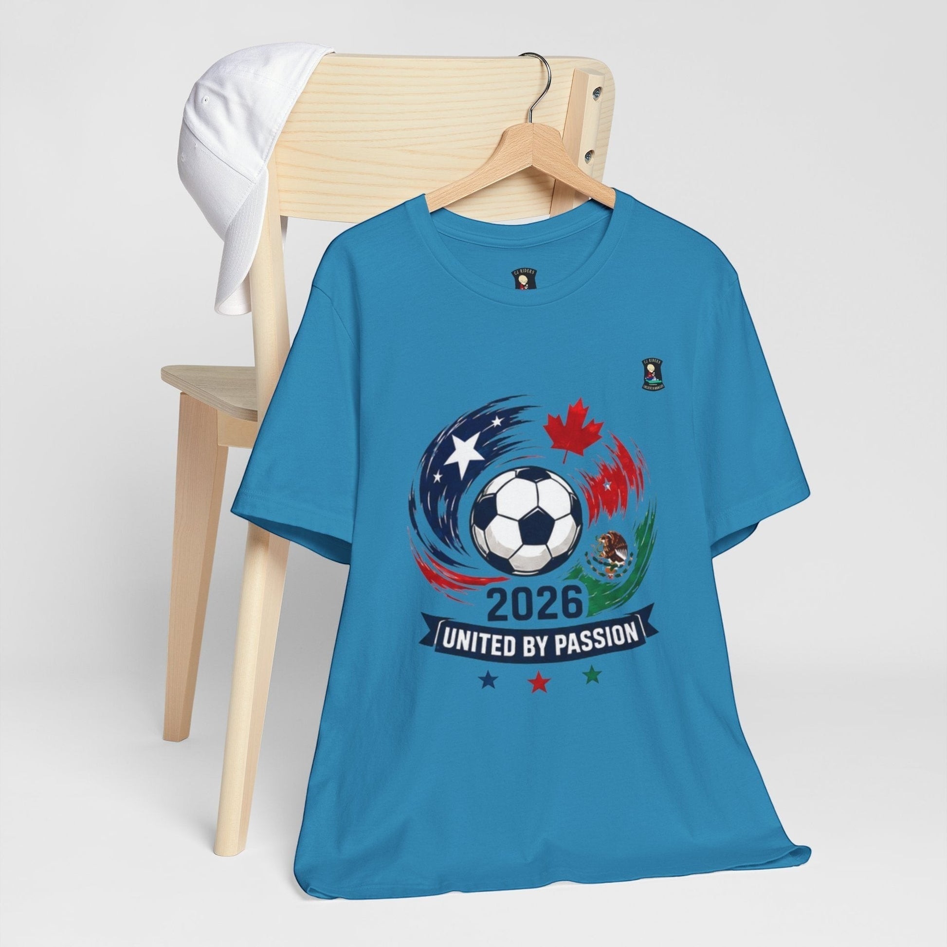 CJ Riders Foundation Store blue 100% cotton soccer t-shirt with 2026 United by Passion graphic featuring a soccer ball and flags of USA, Canada, and Mexico.