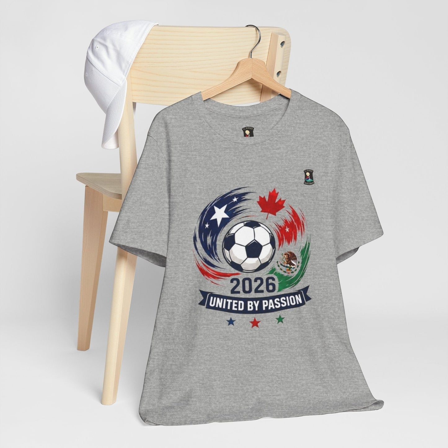CJ Riders Foundation Store grey 100% cotton t-shirt with 2026 soccer graphic featuring USA, Canada, Mexico flags and 'United by Passion' text.