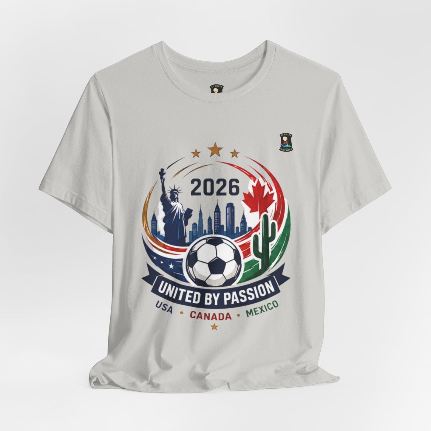 CJ Riders Foundation Store light grey 100% cotton t-shirt with 2026 soccer graphic featuring Statue of Liberty, skyline, soccer ball, Canadian maple leaf, and cactus.