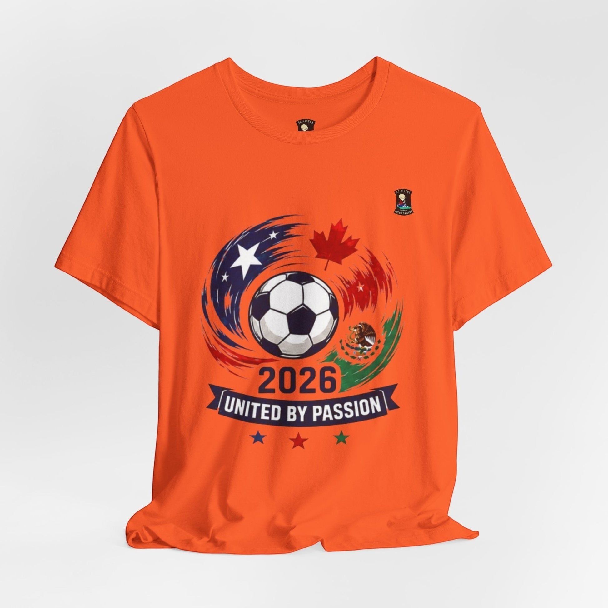 CJ Riders Foundation Store orange 100% cotton t-shirt with 2026 soccer graphic featuring USA, Canada, Mexico flags and a soccer ball.