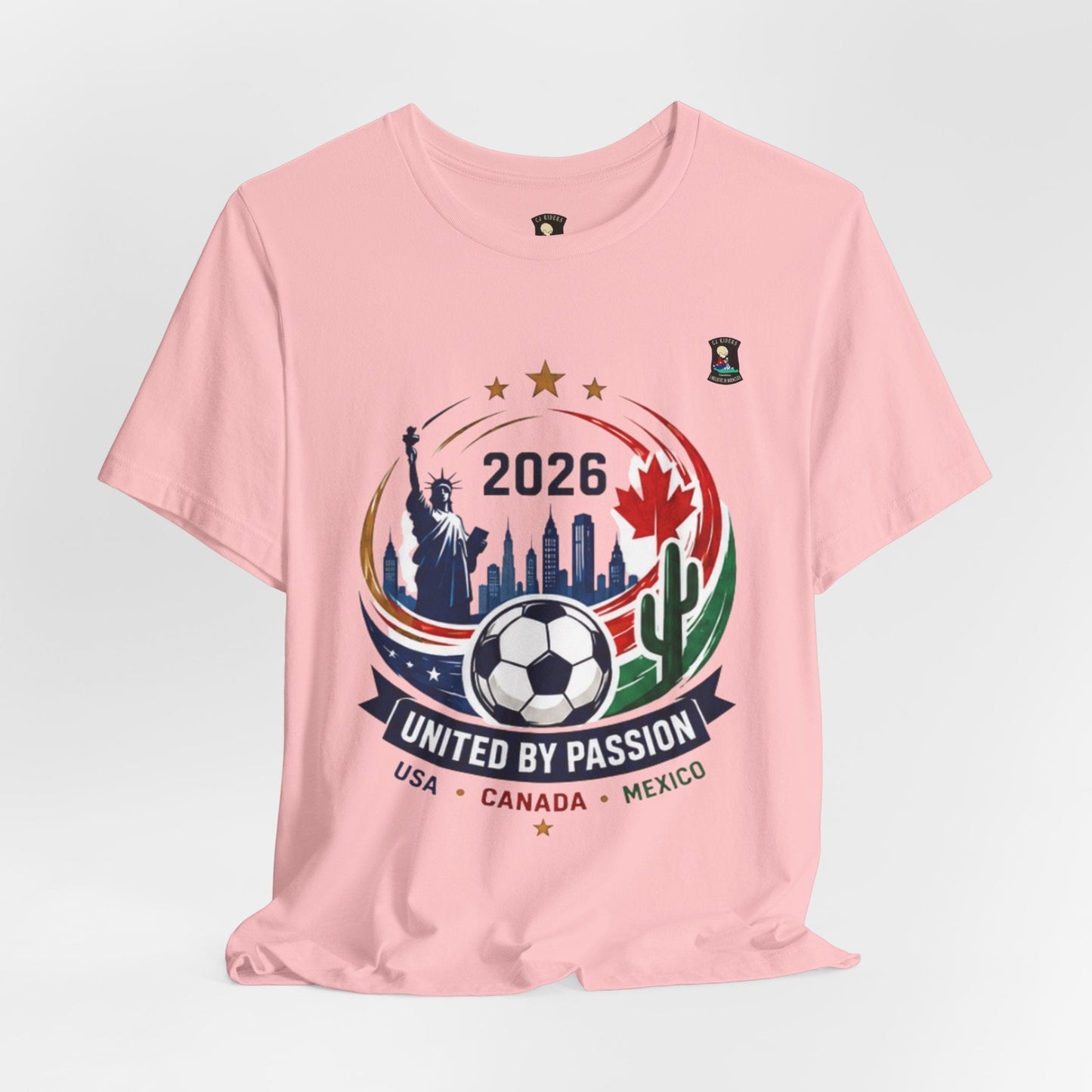 CJ Riders Foundation Store pink 100% cotton t-shirt with 2026 soccer graphic featuring Statue of Liberty, Canadian maple leaf, Mexican cactus, and soccer ball.