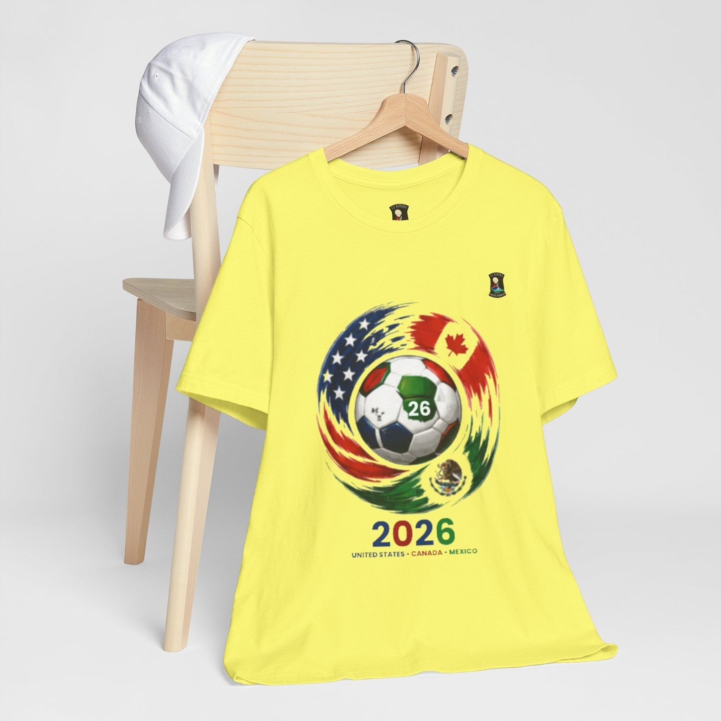 CJ Riders Foundation Store yellow 100% cotton t-shirt with 2026 soccer graphic featuring USA, Canada, Mexico flags.