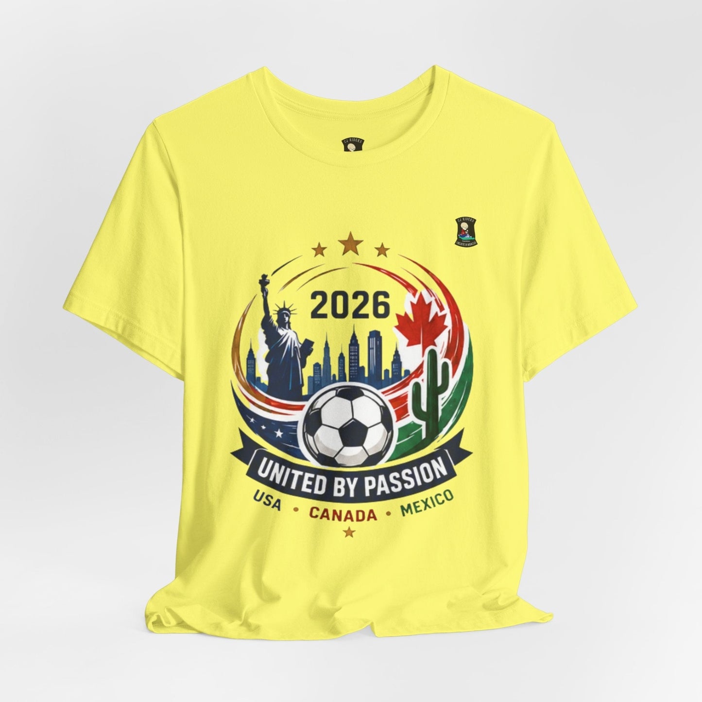 CJ Riders Foundation Store yellow 100% cotton t-shirt with 2026 soccer graphic featuring Statue of Liberty, Canadian maple leaf, Mexican flag, and soccer ball.