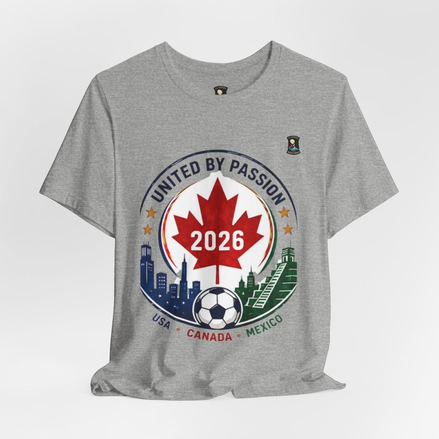 CJ Riders Foundation Store grey 100% cotton t-shirt with a 2026 soccer crest design featuring a red maple leaf, soccer ball, and USA, Canada, Mexico landmarks.