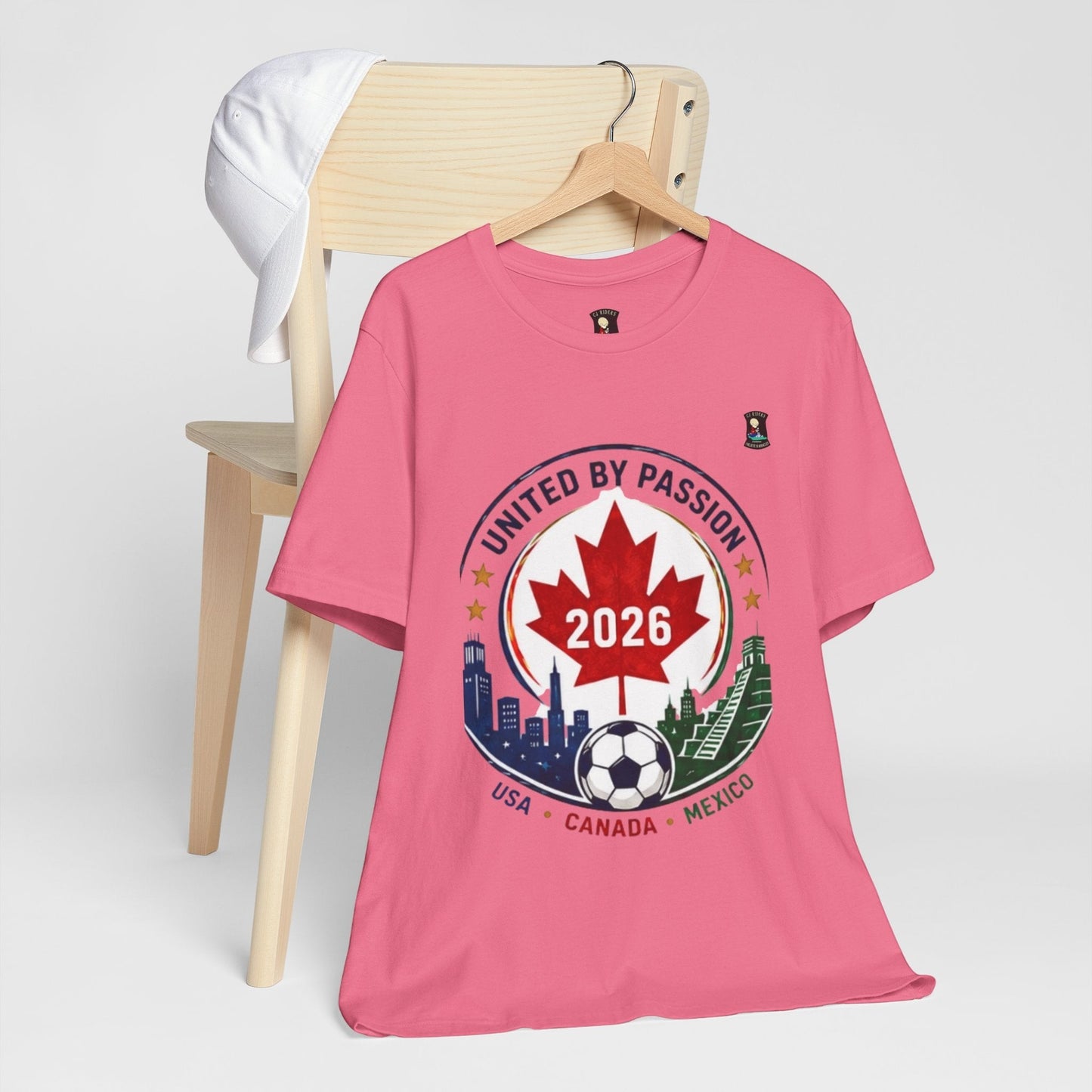CJ Riders Foundation Store pink cotton t-shirt with 2026 soccer crest design featuring Canada, USA, Mexico skylines and soccer ball.