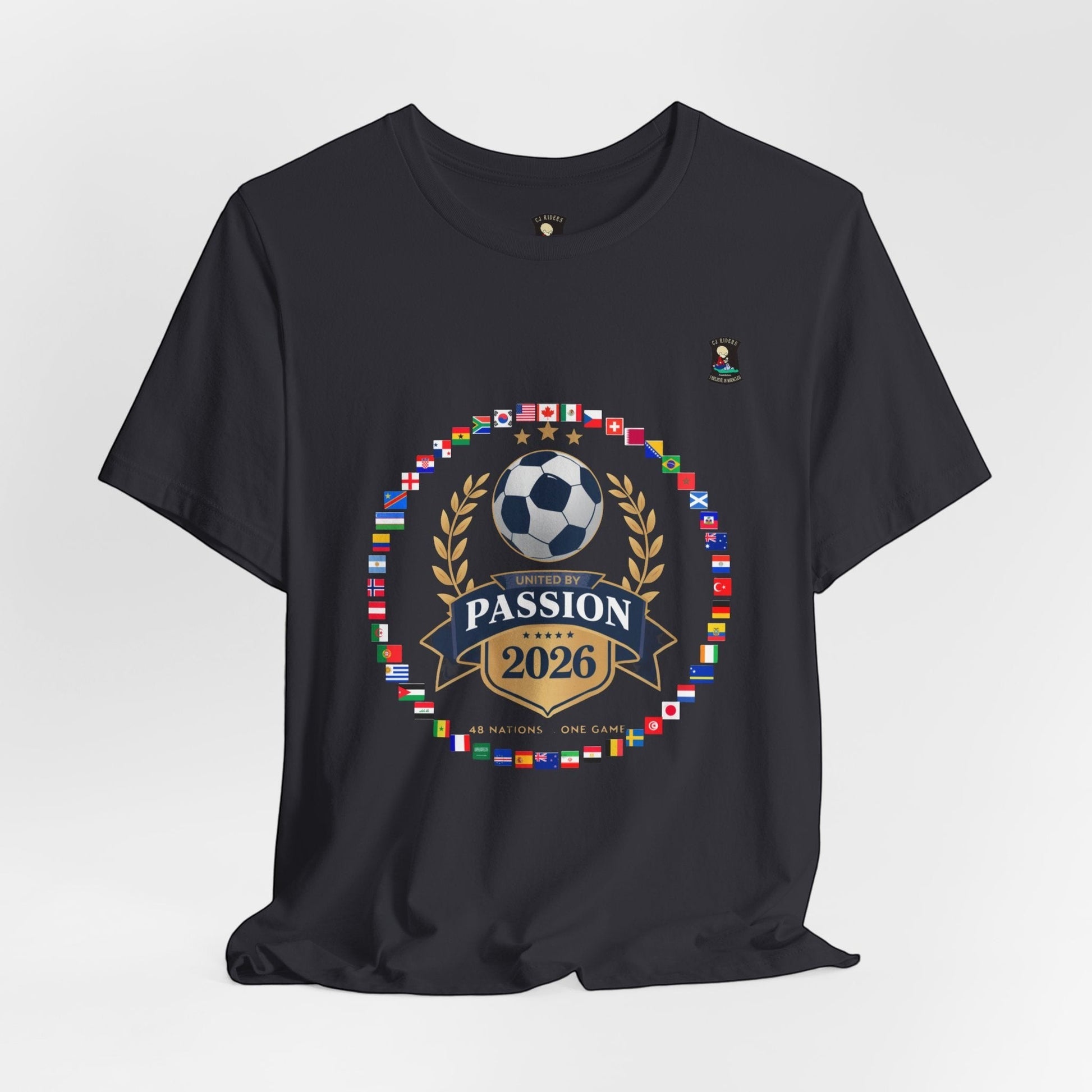 CJ Riders Foundation Store dark grey 100% cotton t-shirt with 2026 World Cup graphic featuring a soccer ball, flags, and "United by Passion" text.