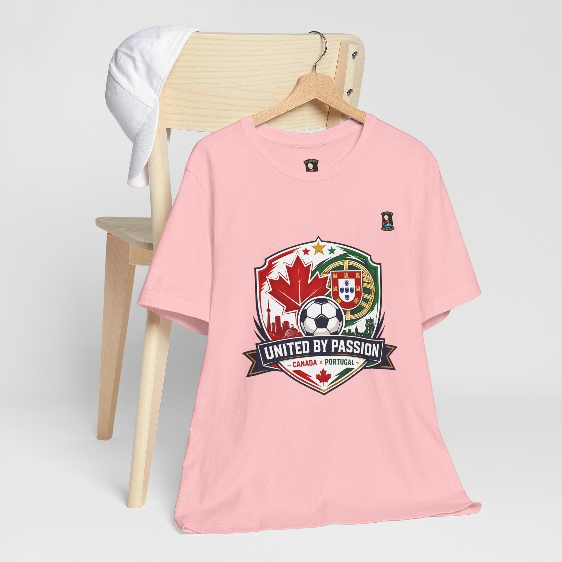 CJ Riders Foundation Store pink 100% cotton t-shirt with Canada & Portugal soccer badge graphic. Features "United by Passion" text.