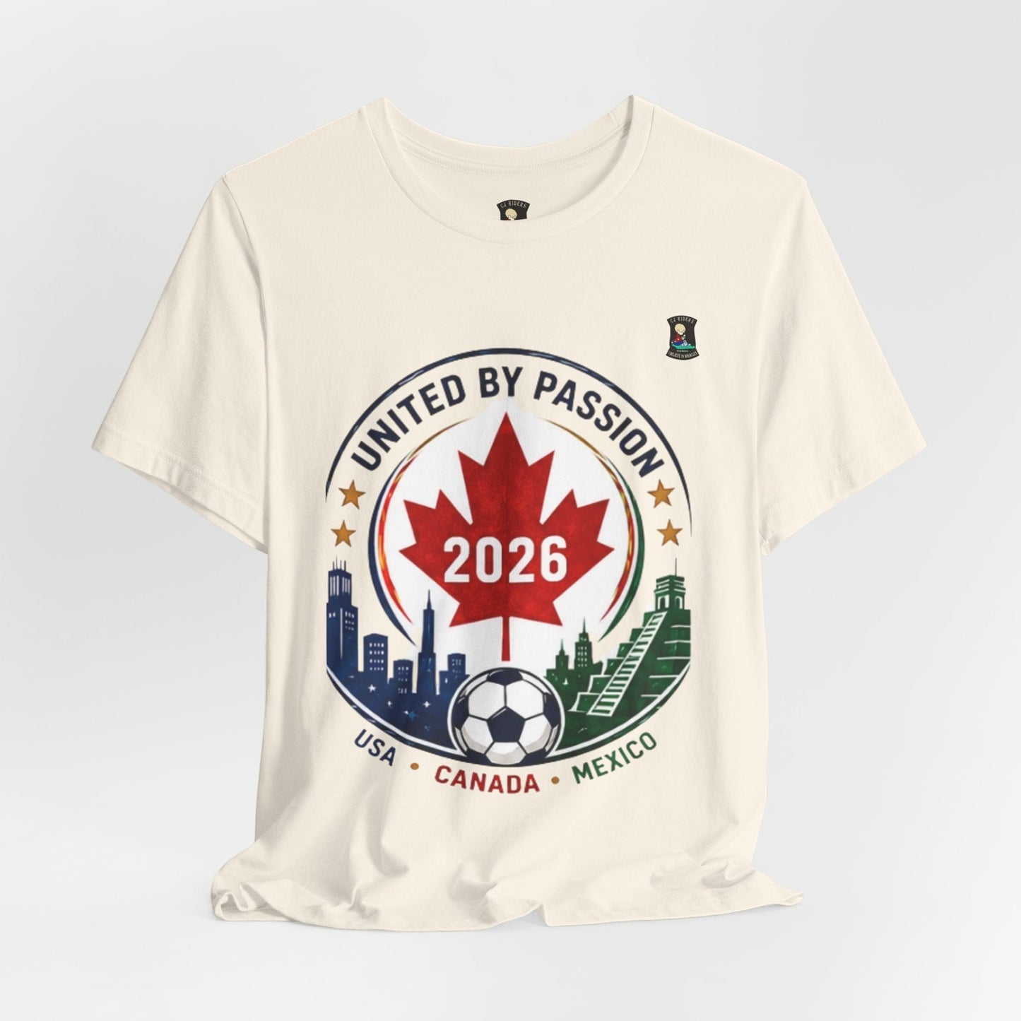CJ Riders Foundation Store cream 100% cotton t-shirt with "United by Passion 2026" soccer crest design featuring Canadian maple leaf, soccer ball, and city/landmark graphics.