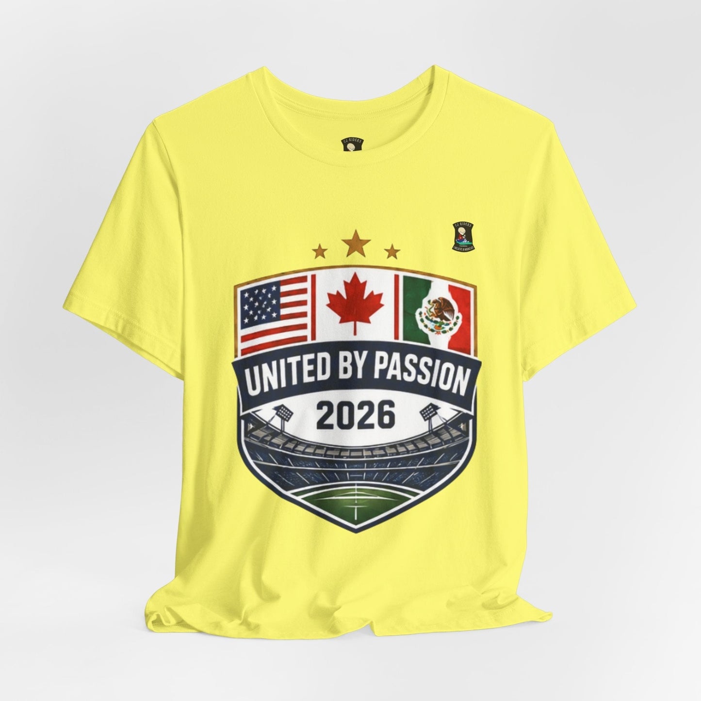 CJ Riders Foundation Store yellow 100% cotton t-shirt with United by Passion 2026 shield graphic featuring USA, Canada, Mexico flags and stadium.