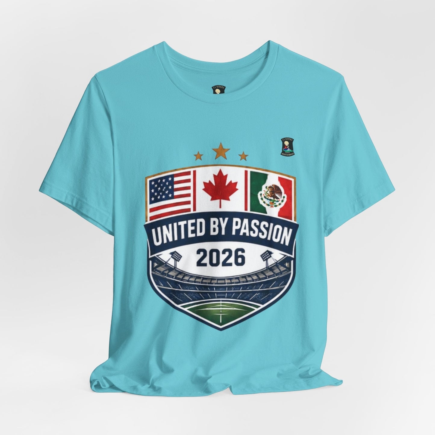 CJ Riders Foundation Store light blue 100% cotton t-shirt with a shield design featuring US, Canadian, and Mexican flags and "United by Passion 2026" text.