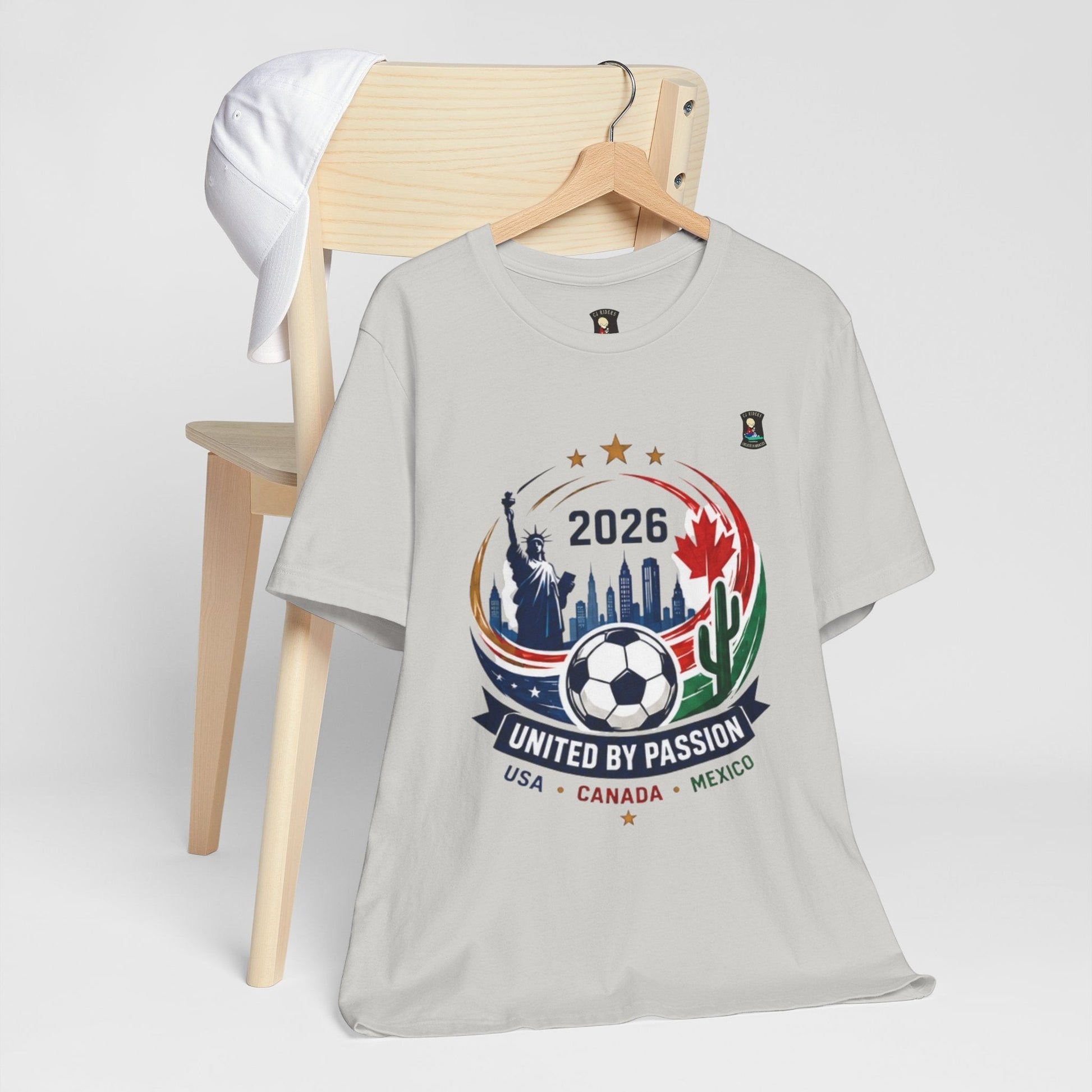 CJ Riders Foundation Store light grey 100% cotton t-shirt with 2026 soccer graphic featuring USA, Canada, Mexico.