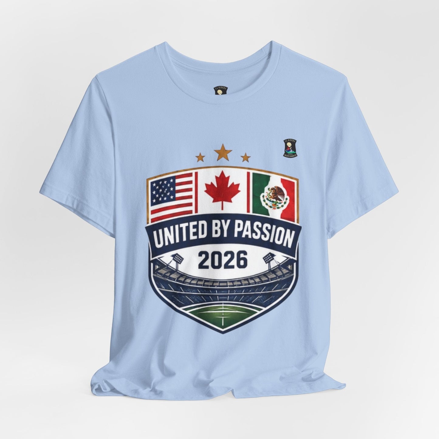 CJ Riders Foundation Store light blue 100% cotton t-shirt with United by Passion 2026 shield graphic featuring US, Canadian, and Mexican flags.