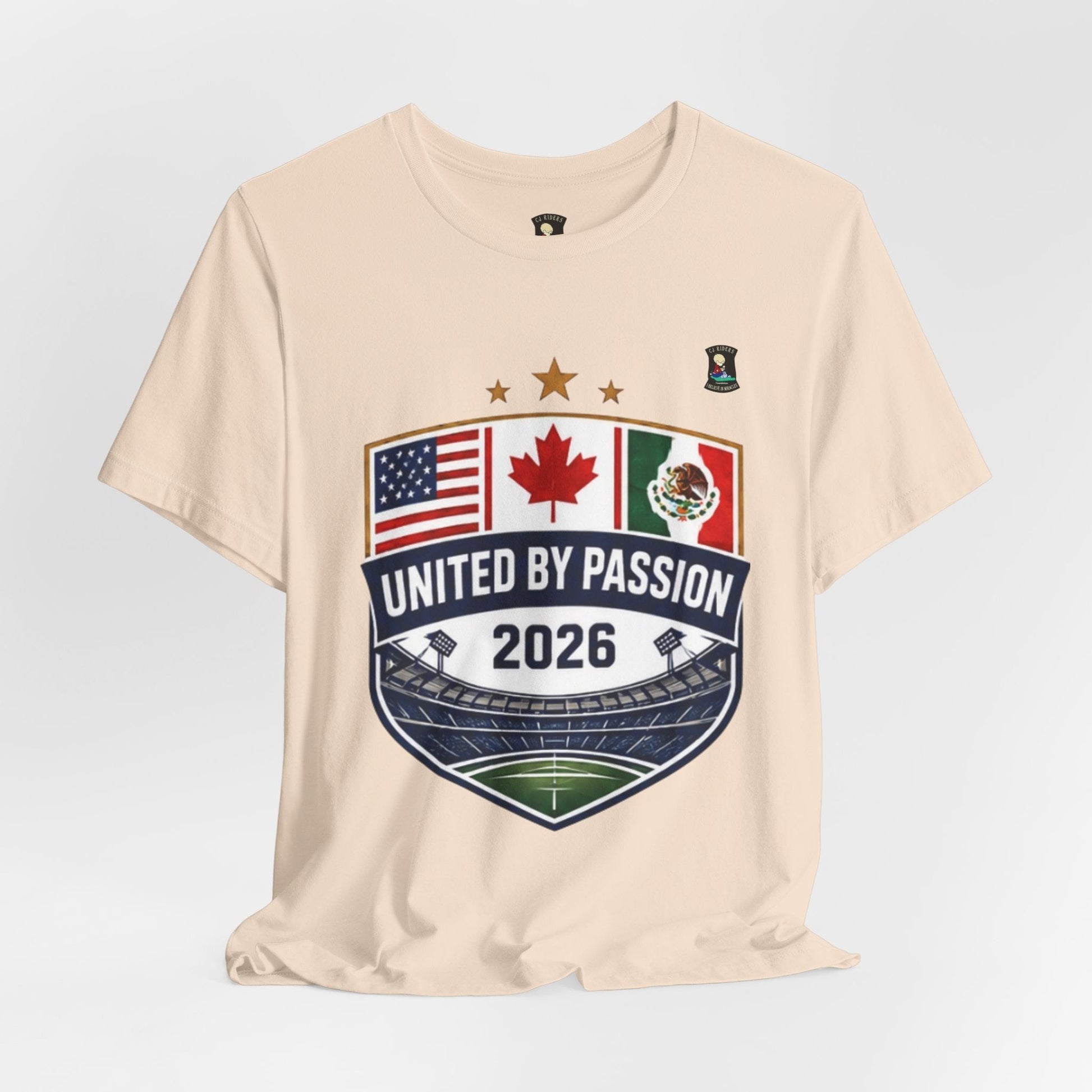 CJ Riders Foundation Store cream 100% cotton t-shirt with United by Passion 2026 shield design featuring USA, Canada, Mexico flags and stadium graphic.