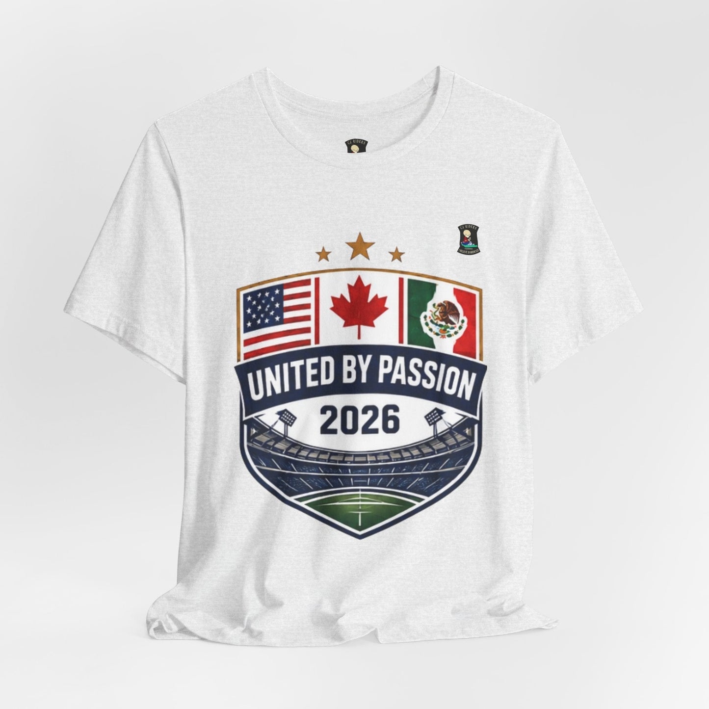 White 100% cotton t-shirt with a shield design featuring USA, Canada, and Mexico flags, "United by Passion 2026" text, and stadium graphic. CJ Riders Foundation Store.