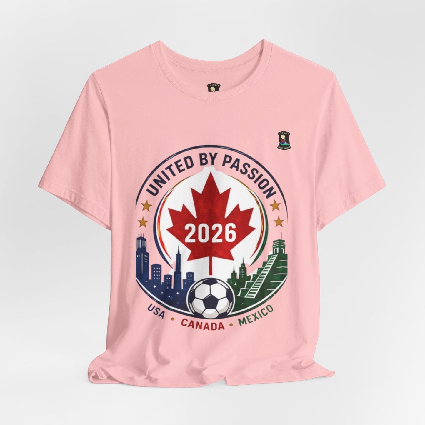 CJ Riders Foundation Store pink 100% cotton t-shirt with a "United by Passion 2026" graphic featuring a Canadian maple leaf, soccer ball, and city skylines from USA, Canada, and Mexico.