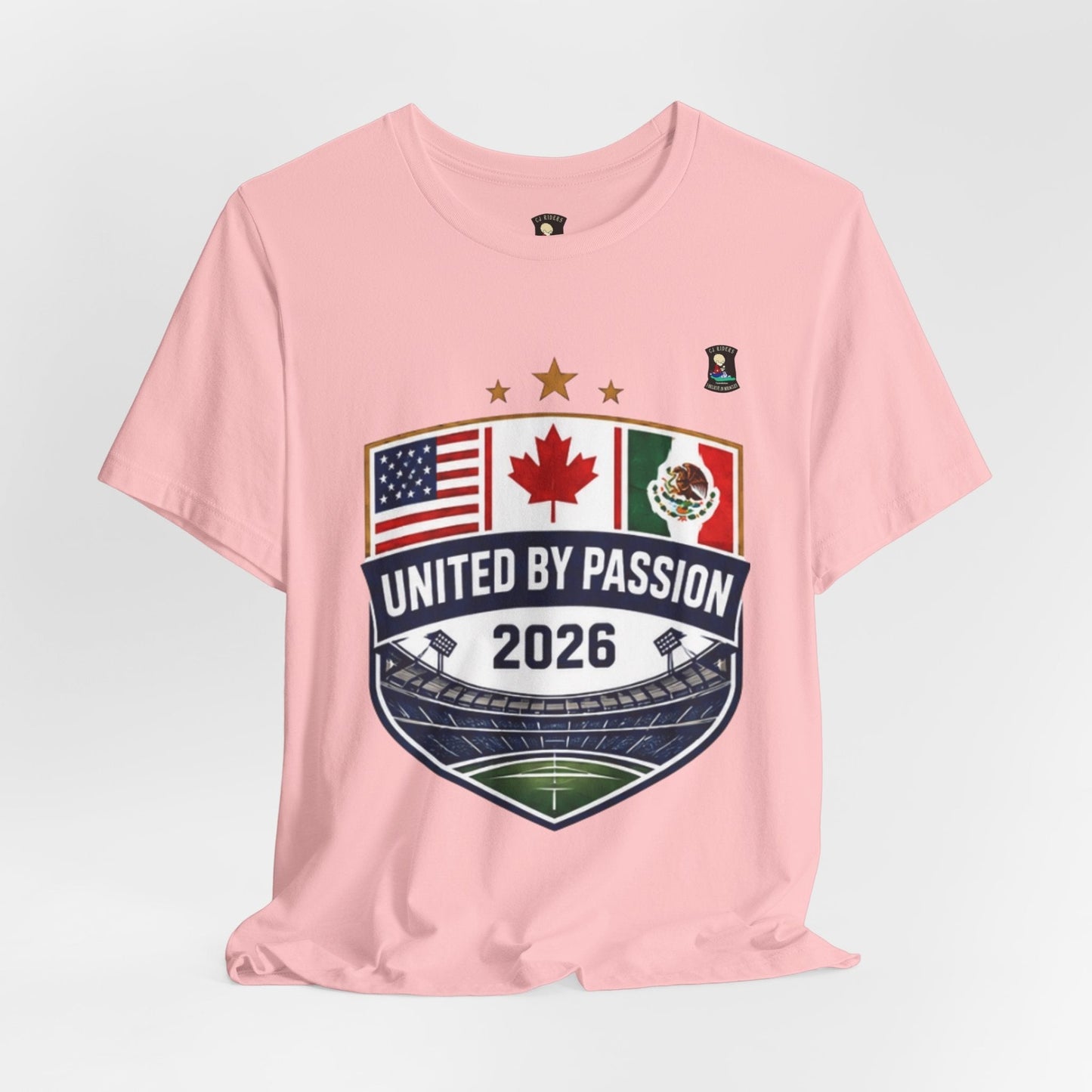 CJ Riders Foundation Store pink 100% cotton t-shirt with United by Passion 2026 shield design featuring USA, Canada, and Mexico flags.