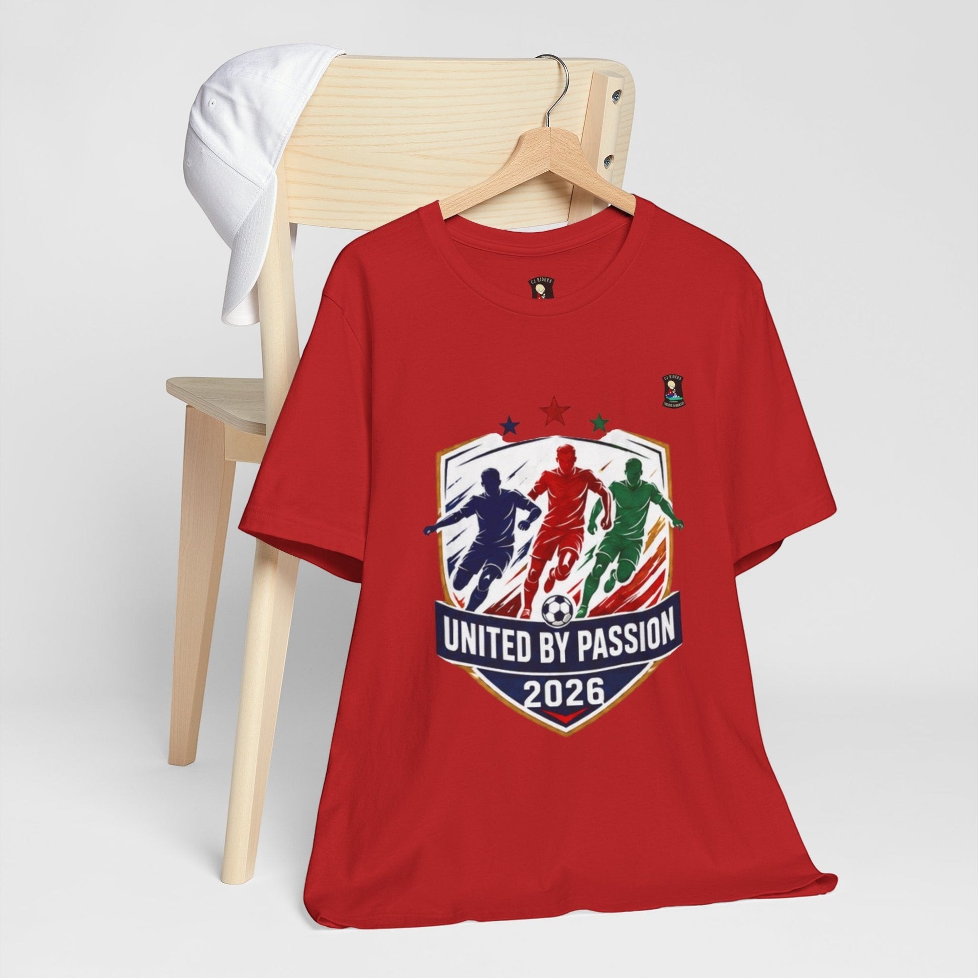 CJ Riders Foundation Store red cotton t-shirt with "United by Passion 2026" soccer graphic featuring 3 players and a ball.