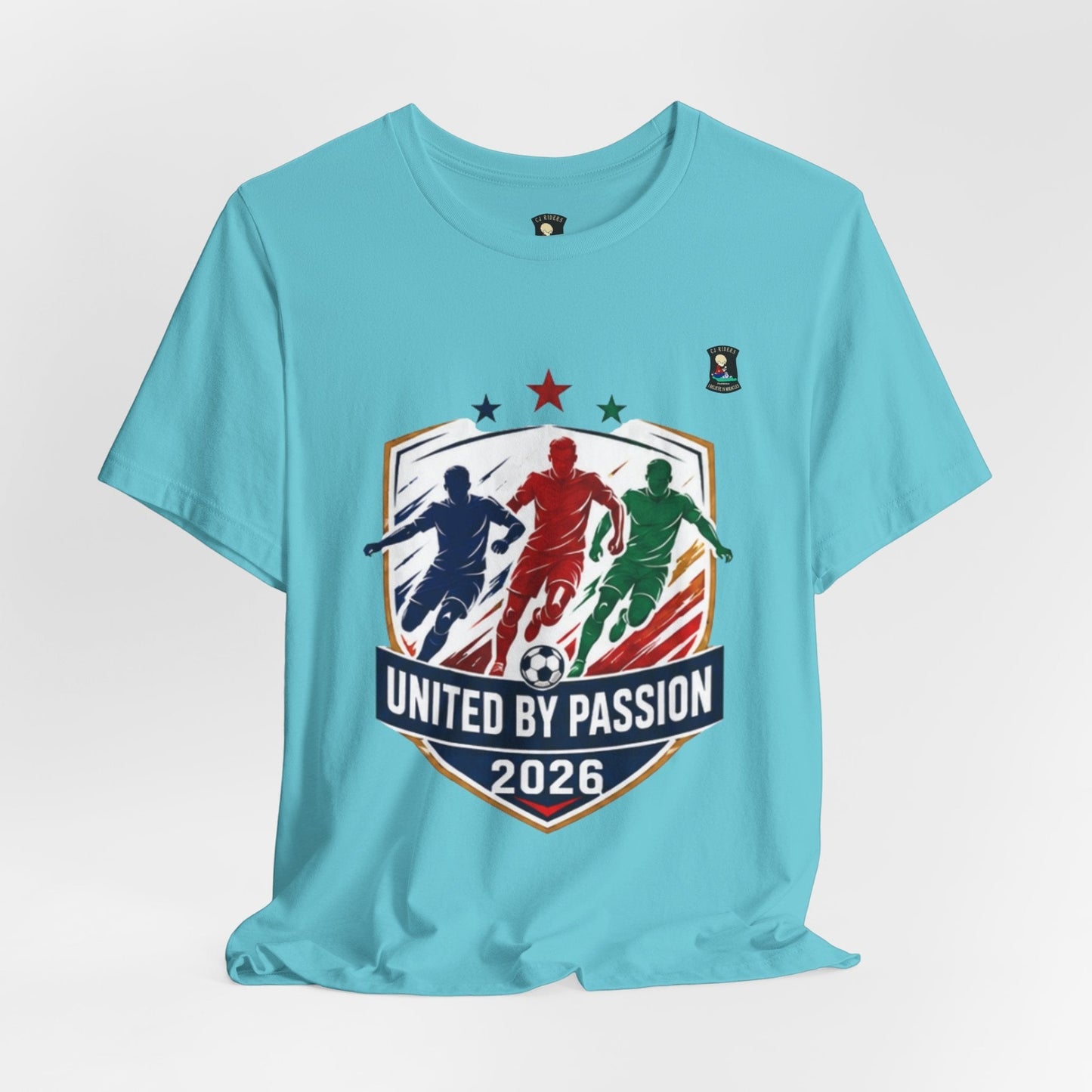CJ Riders Foundation Store light blue 100% cotton t-shirt with "United by Passion 2026" graphic featuring three soccer players and a ball.
