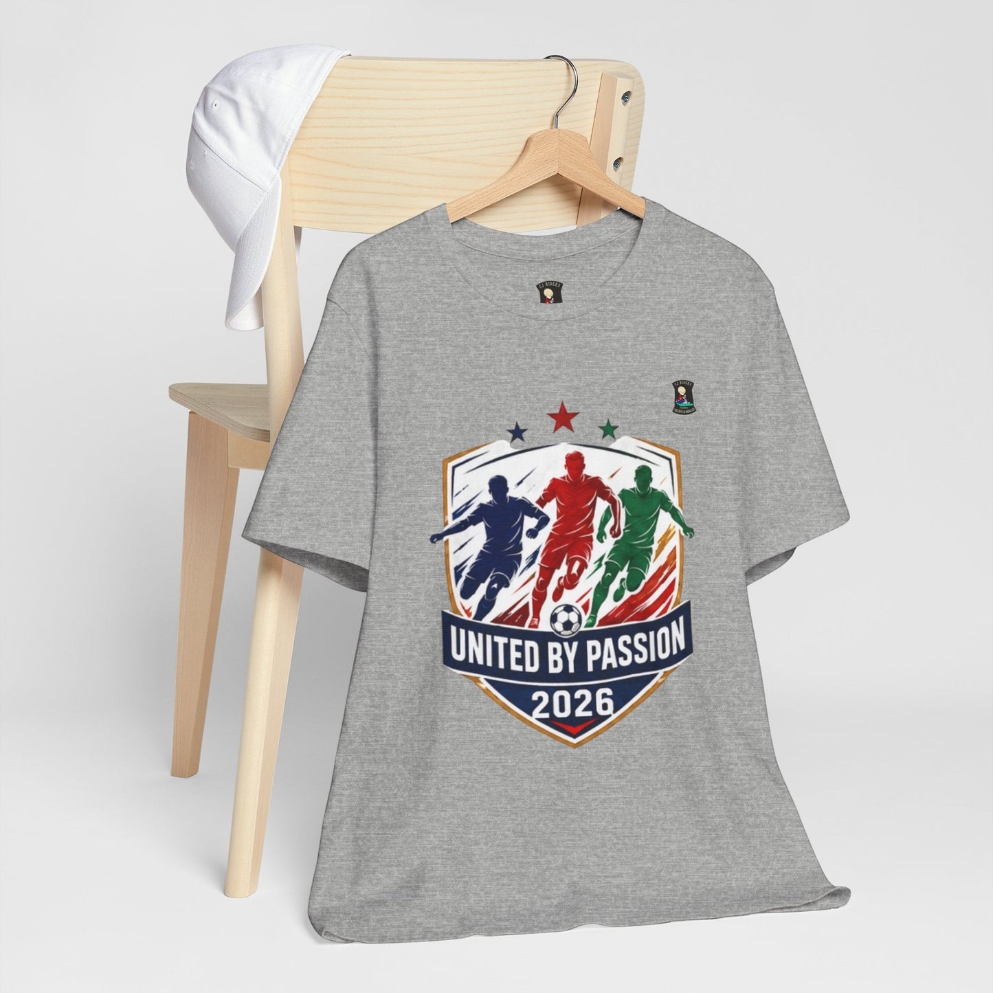CJ Riders Foundation Store grey 100% cotton t-shirt with soccer graphic and "United by Passion 2026" text.