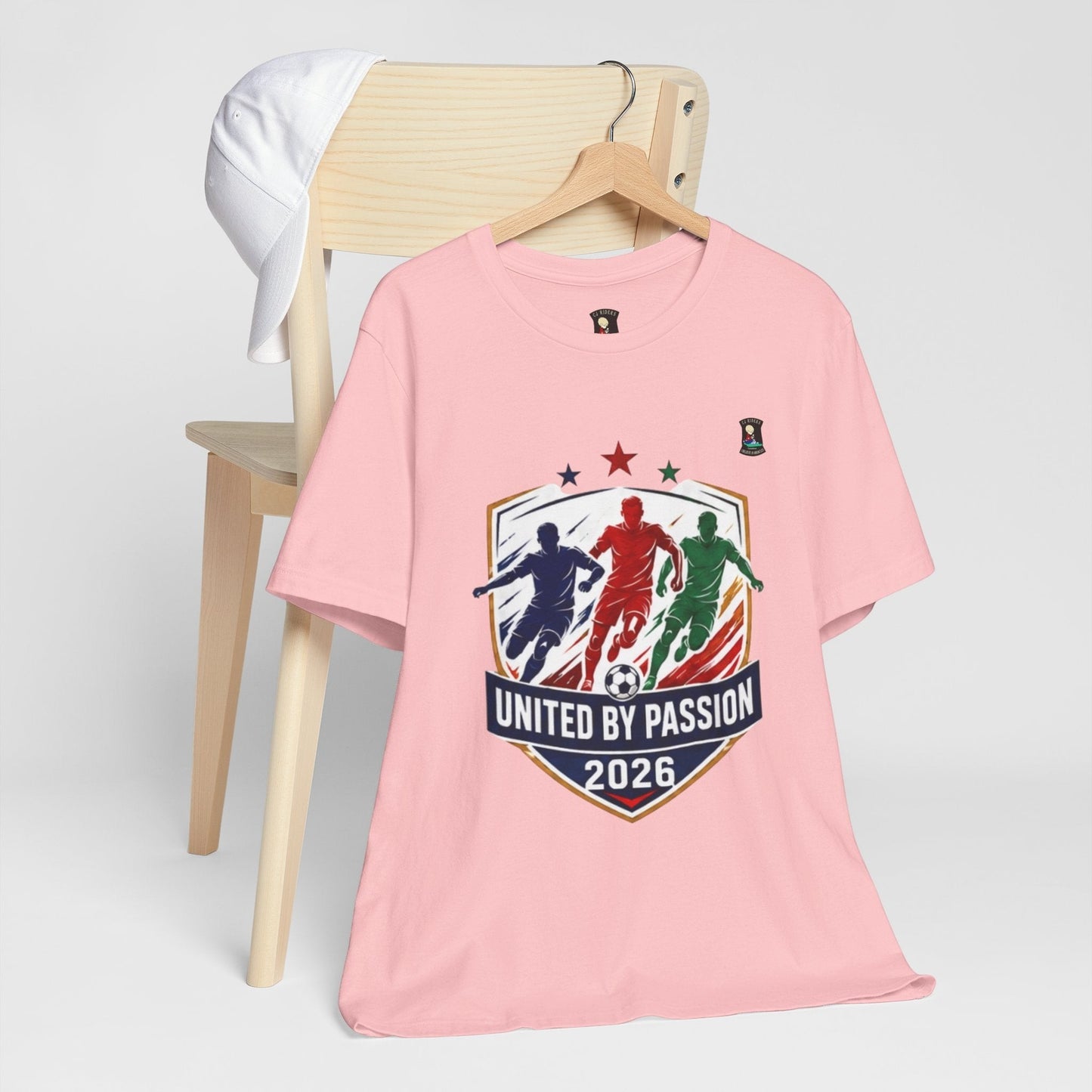 CJ Riders Foundation Store pink 100% cotton t-shirt with "United by Passion 2026" soccer graphic featuring three players.