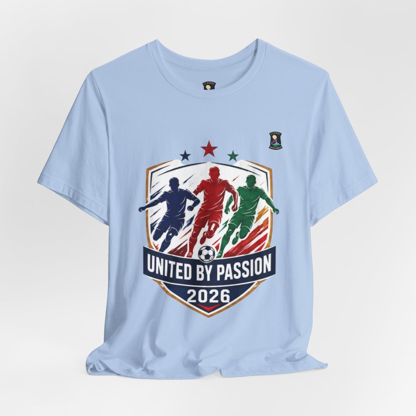 CJ Riders Foundation Store light blue 100% cotton t-shirt with "United by Passion 2026" soccer graphic featuring three players and a ball.