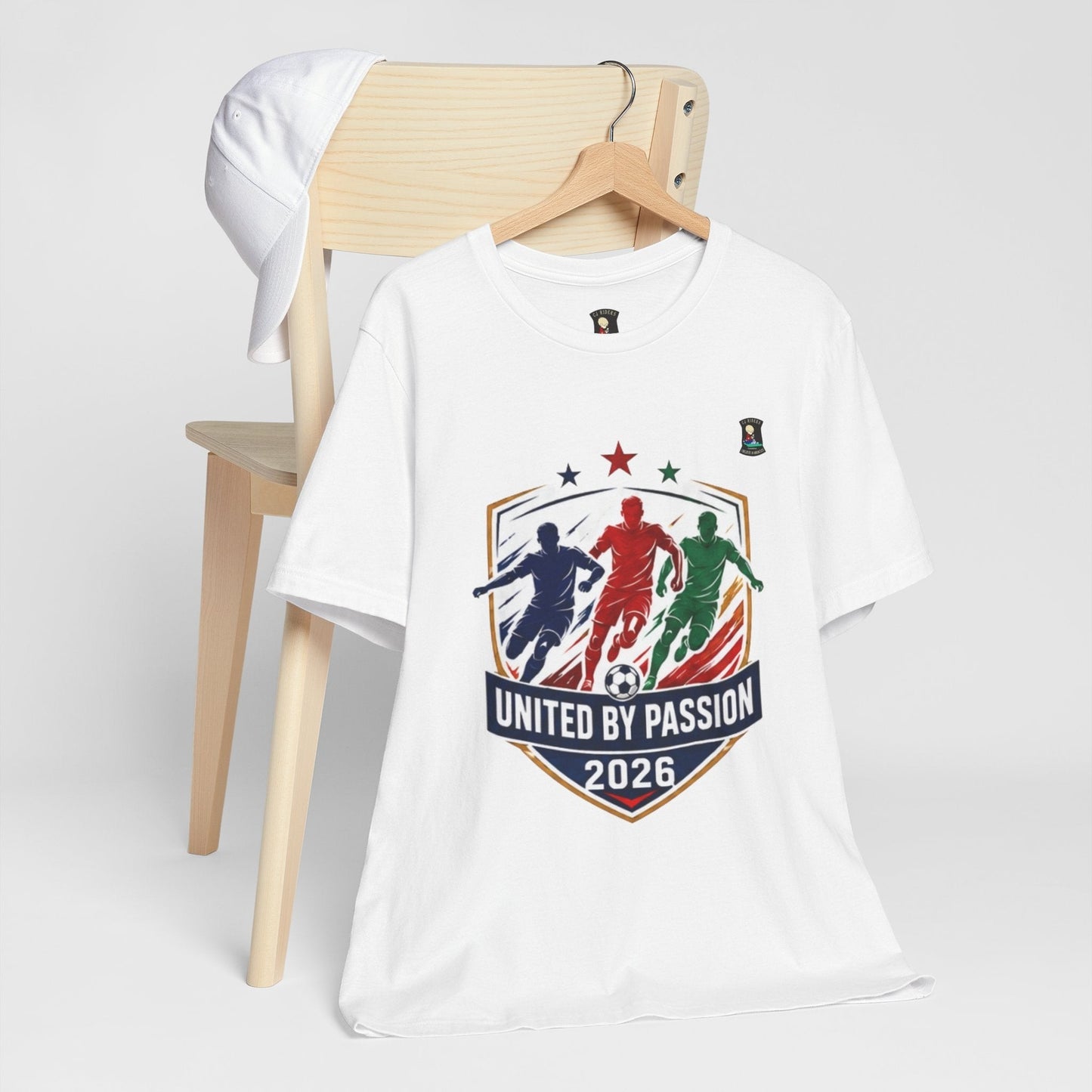 CJ Riders Foundation Store white 100% cotton t-shirt with "United by Passion 2026" soccer graphic featuring 3 players and a ball.