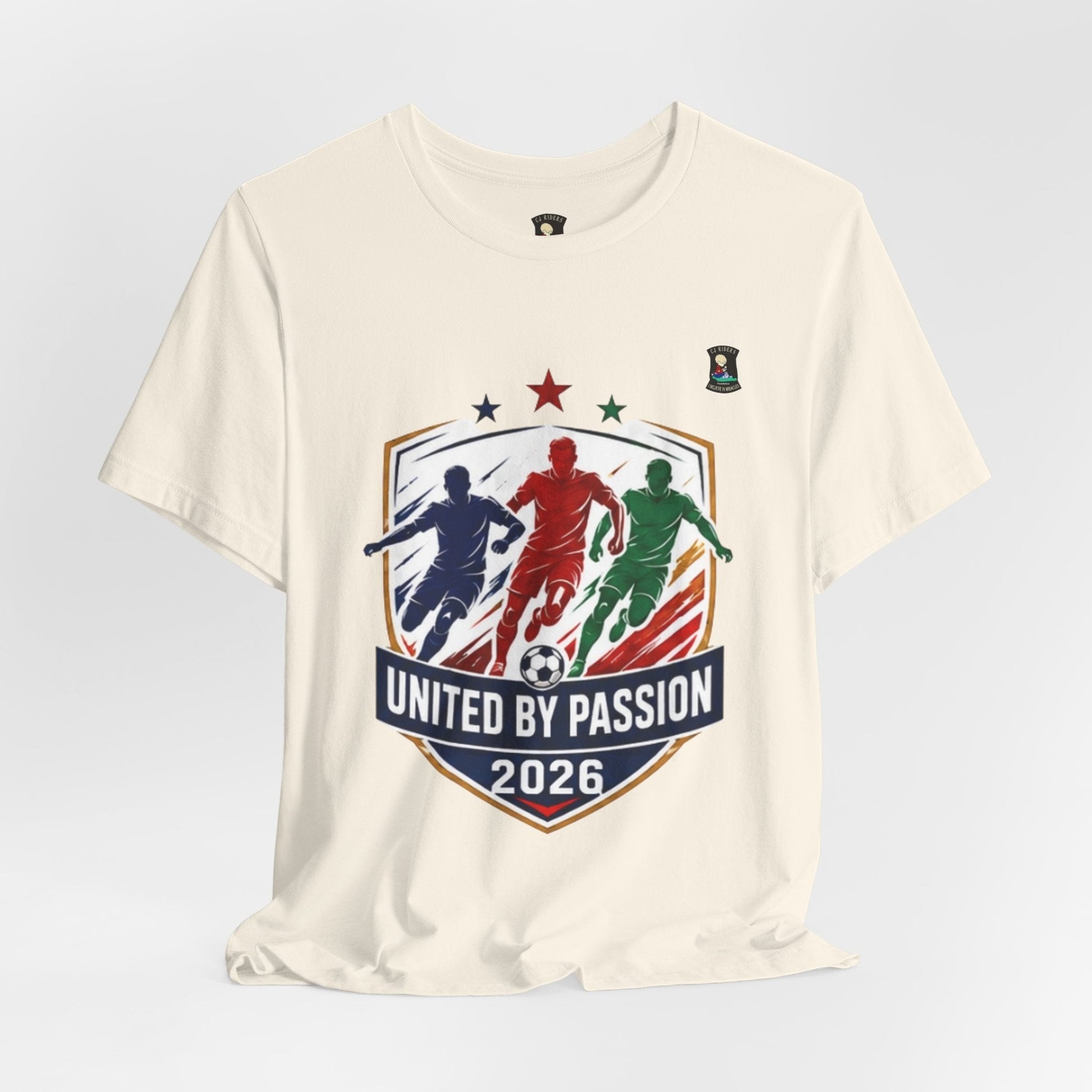 CJ Riders Foundation Store cream 100% cotton t-shirt with "United by Passion 2026" graphic featuring 3 soccer players and a ball.
