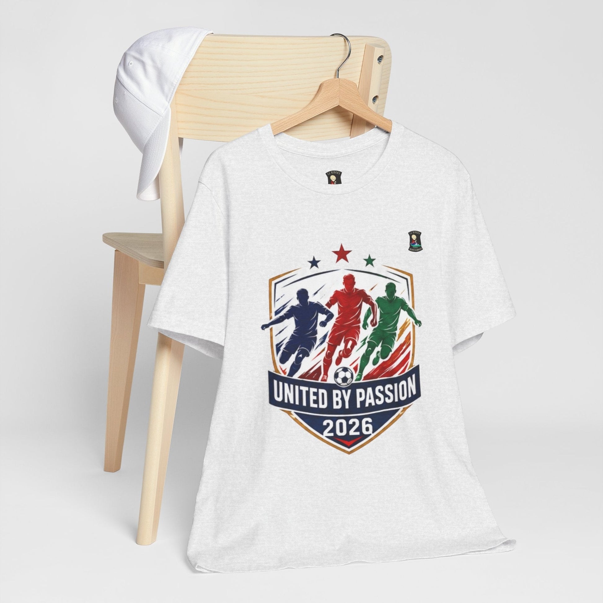 CJ Riders Foundation Store white 100% cotton t-shirt with "United by Passion 2026" graphic featuring 3 soccer players.