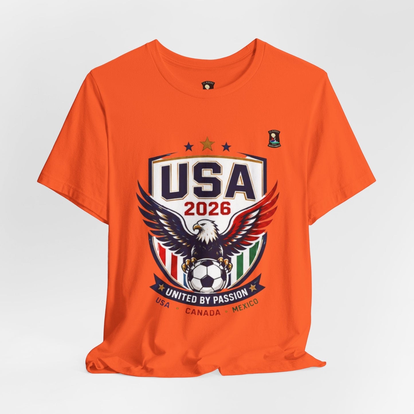 CJ Riders Foundation Store orange 100% cotton t-shirt with USA 2026 soccer graphic featuring an eagle and soccer ball.