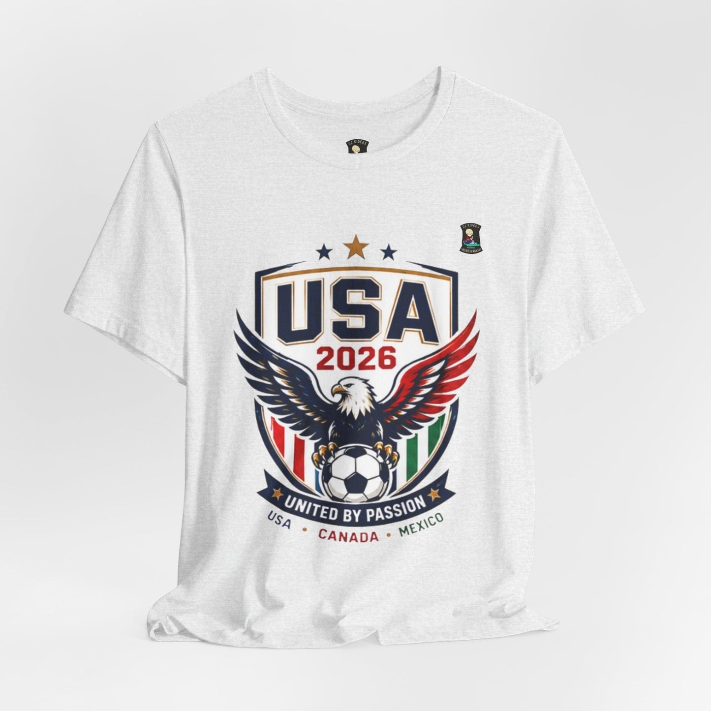 CJ Riders Foundation Store white 100% cotton t-shirt with USA 2026 eagle and soccer ball graphic. Features red, white, blue, and green accents.
