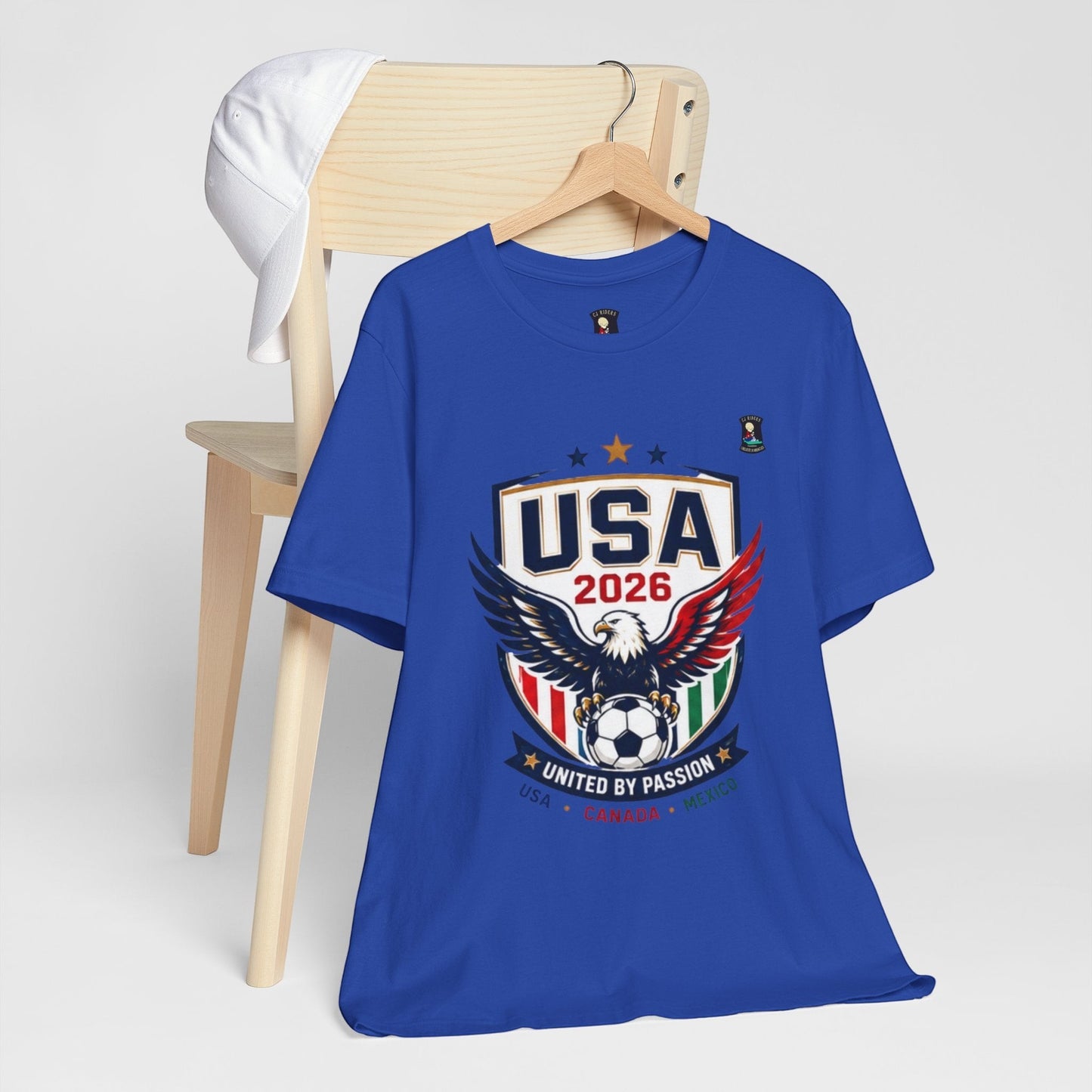 CJ Riders Foundation Store royal blue 100% cotton t-shirt with USA 2026 eagle and soccer ball graphic. Features patriotic colors.