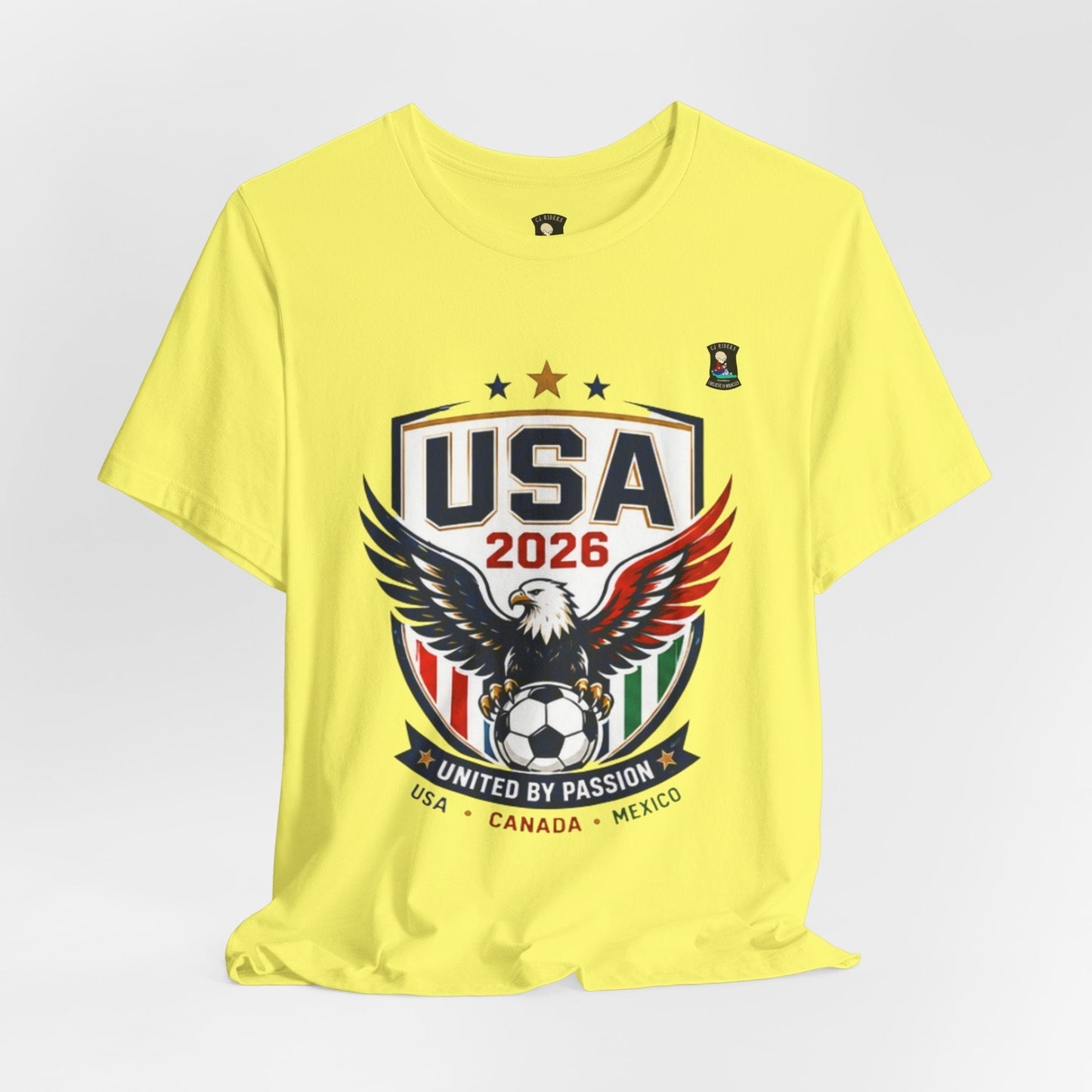 CJ Riders Foundation Store yellow 100% cotton t-shirt with USA 2026 soccer graphic, eagle, and patriotic colors.