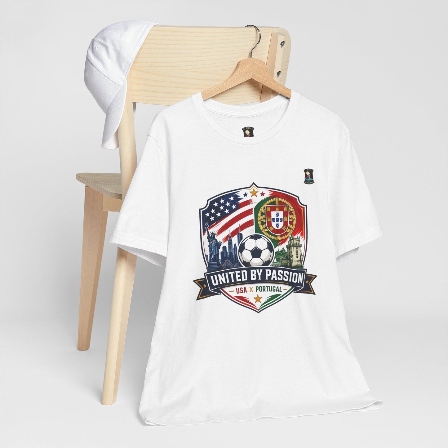 CJ Riders Foundation Store white 100% cotton soccer t-shirt with USA & Portugal flags, Statue of Liberty, soccer ball, and "United by Passion" graphic.