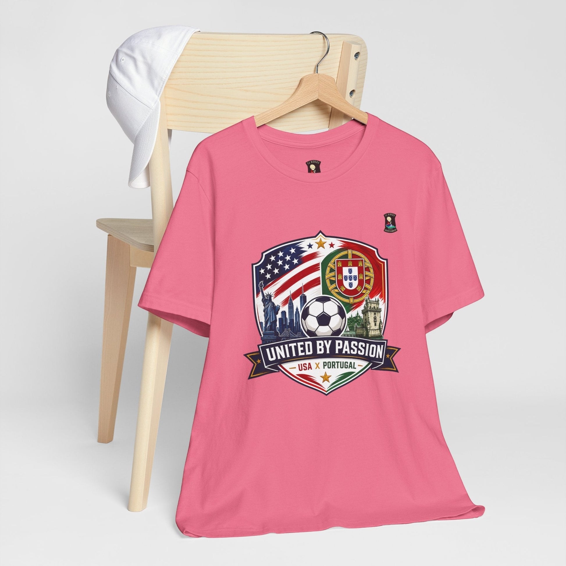 CJ Riders Foundation Store pink cotton t-shirt with USA & Portugal soccer badge graphic, Statue of Liberty, and soccer ball.