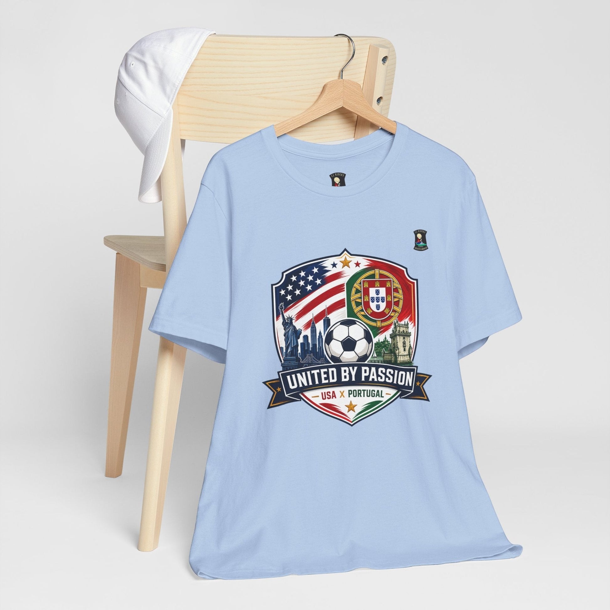 CJ Riders Foundation Store light blue 100% cotton t-shirt with USA & Portugal soccer crest graphic and "United by Passion" text.
