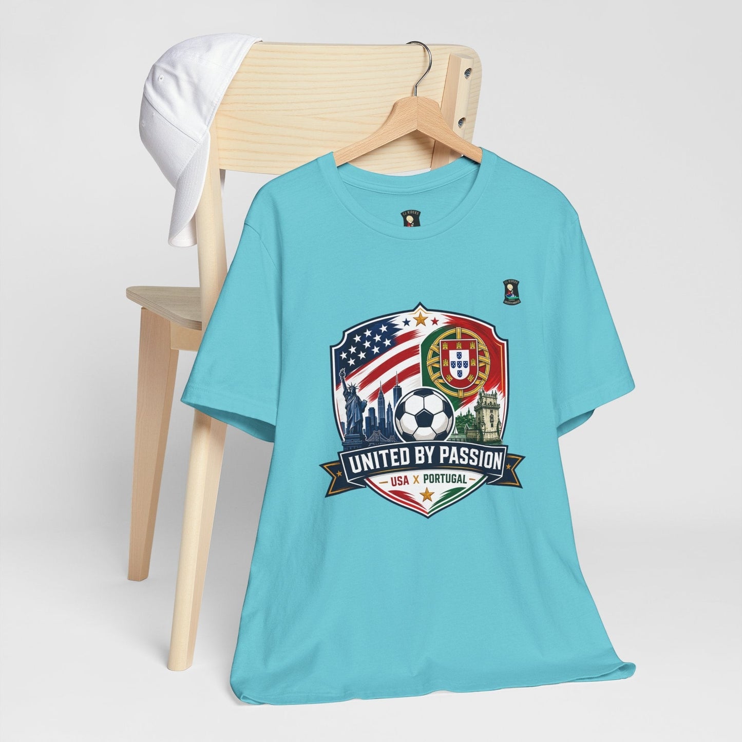 CJ Riders Foundation Store light blue 100% cotton t-shirt with USA & Portugal soccer crest graphic and "United by Passion" text.