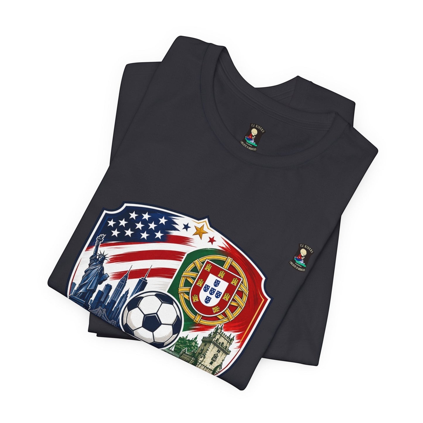 CJ Riders Foundation Store dark grey 100% cotton t-shirt with USA & Portugal soccer badge design, featuring Statue of Liberty, NYC skyline, soccer ball, and Portuguese coat of arms.