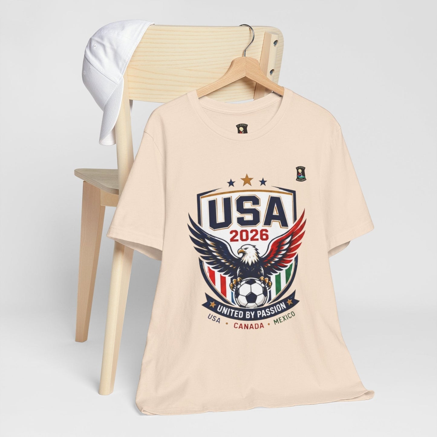 CJ Riders Foundation Store USA United by Passion 2026 soccer t-shirt with eagle graphic in beige 100% cotton.