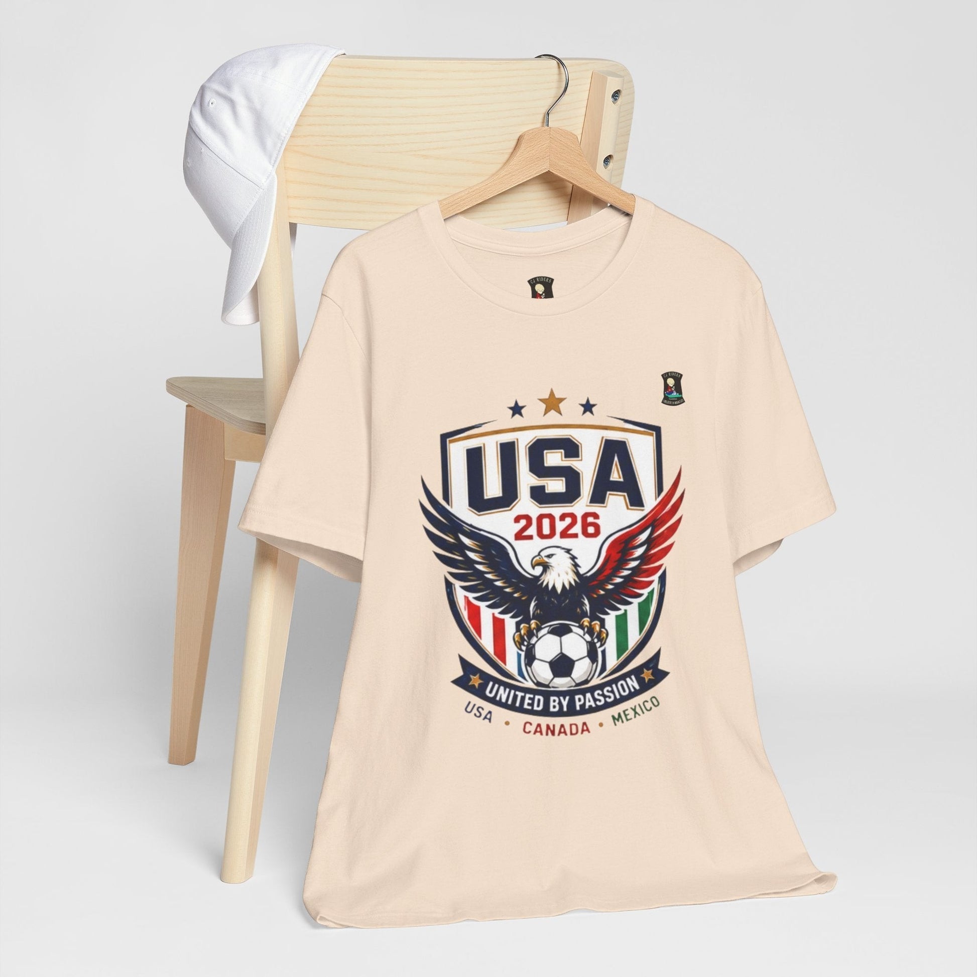CJ Riders Foundation Store USA United by Passion 2026 soccer t-shirt with eagle graphic in beige 100% cotton.